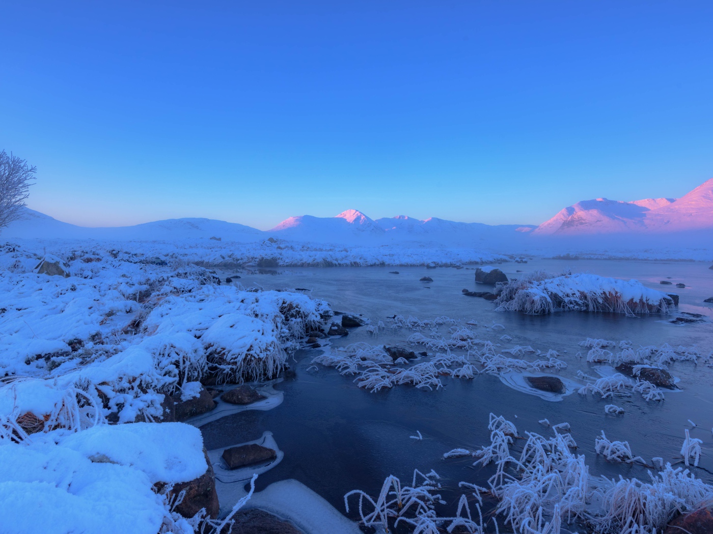 Розовый закат солнца над заснеженными горами и покрытым льдом озером