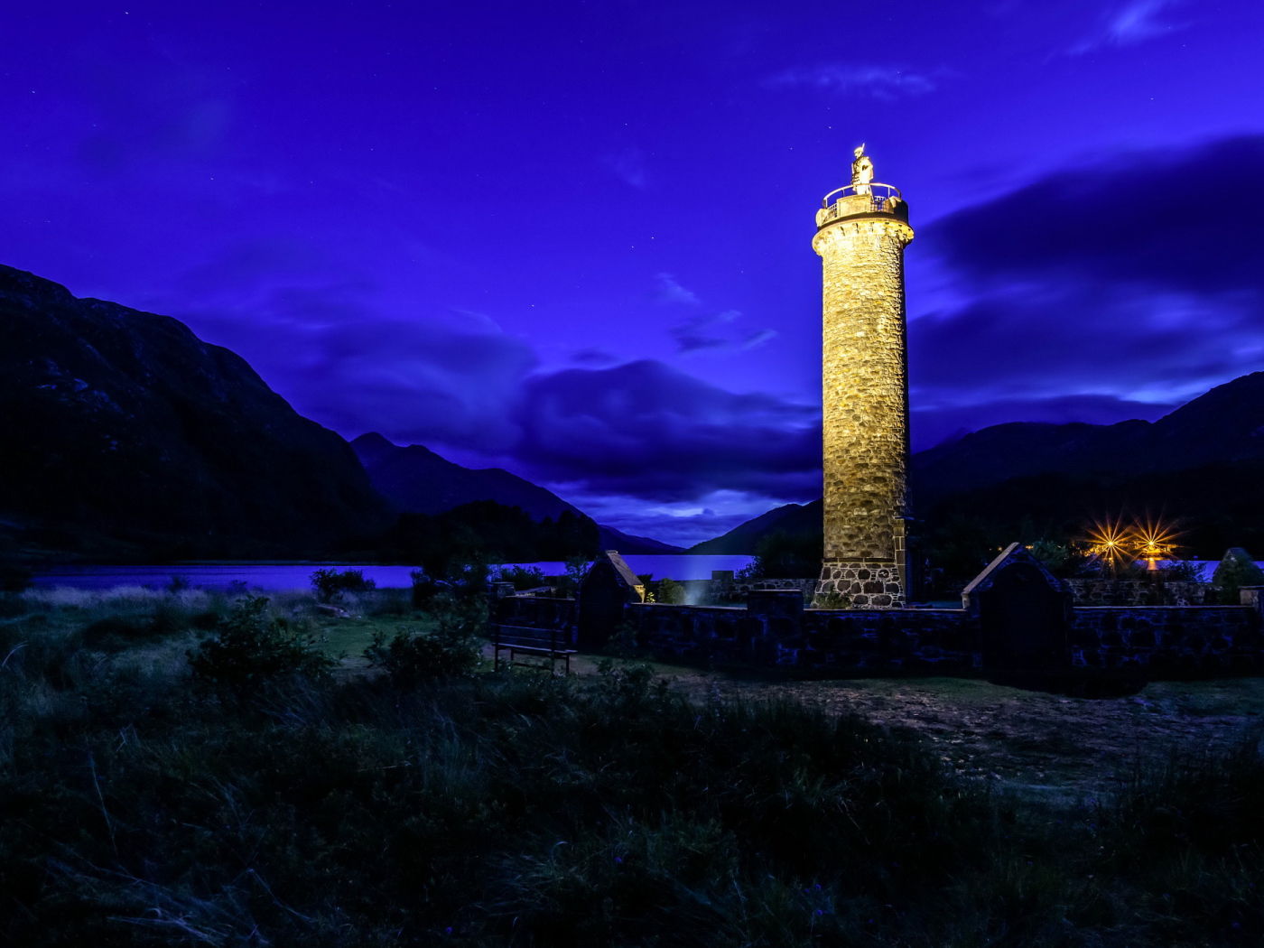 Night lighthouse off the coast in the background of the mountains, the village of Glenfinnan. Scotland