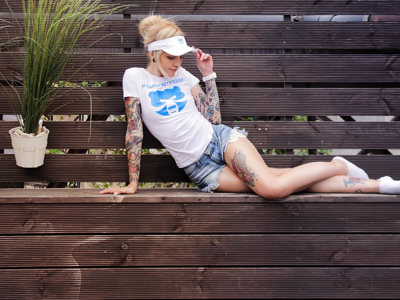 Sports girl in tattoos lies on a wooden bench