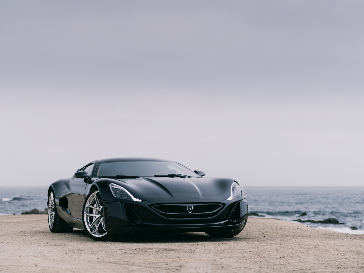 Черный спортивный автомобиль Rimac Concept One на фоне океана