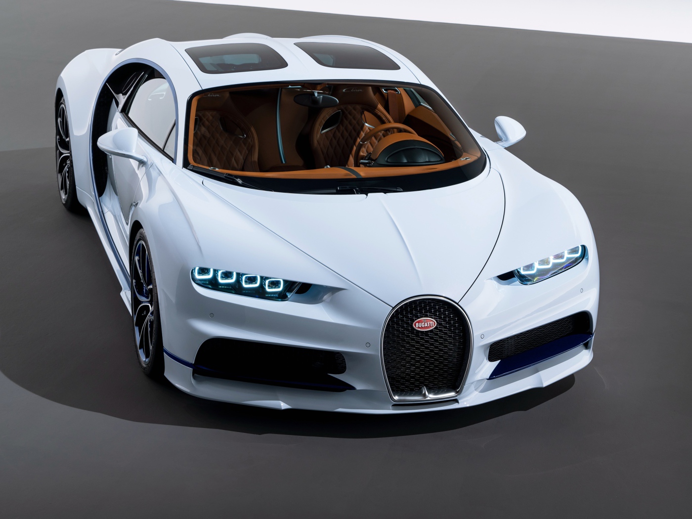 Белый автомобиль bugatti chiron на сером фоне