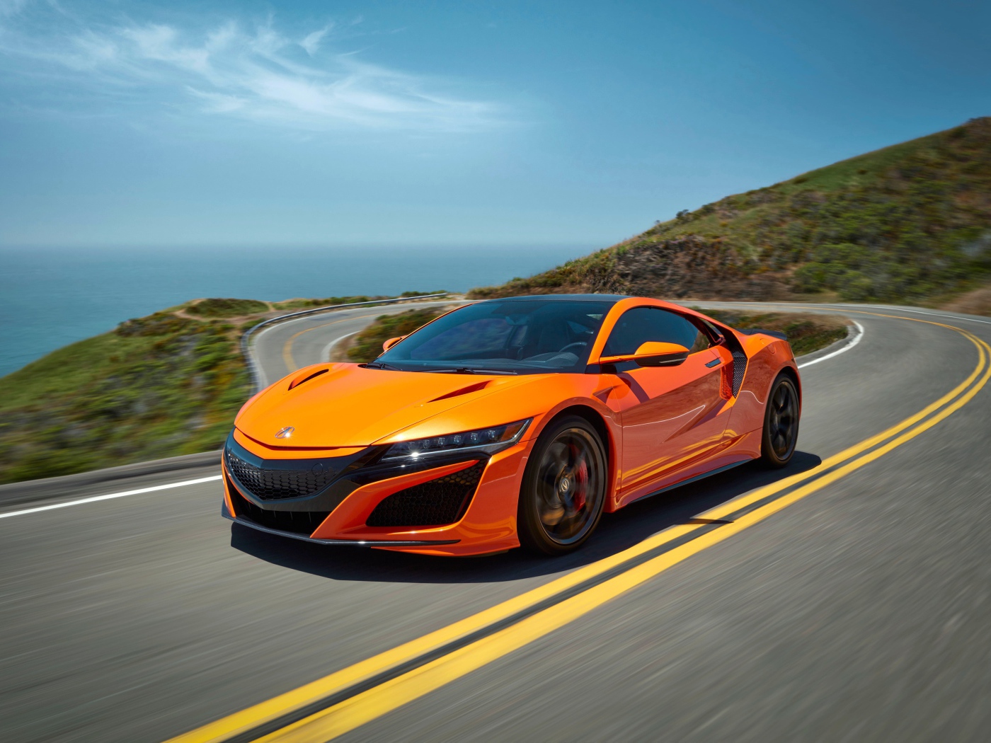 Оранжевый автомобиль Honda NSX на трассе под голубым небом