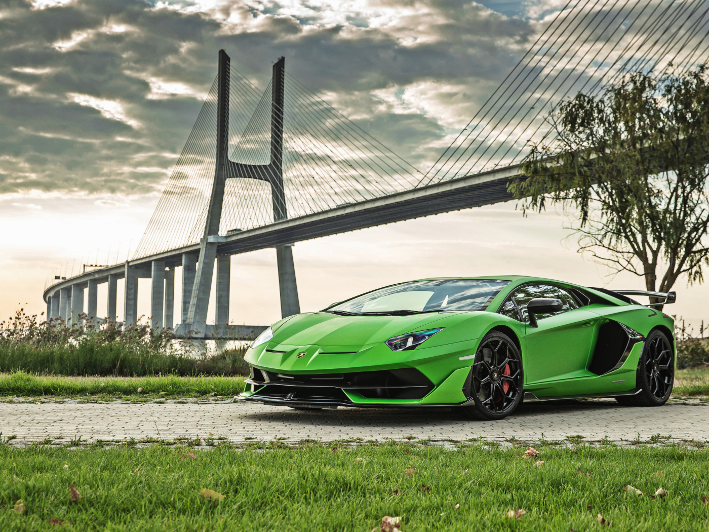 Зеленый дорогой автомобиль Lamborghini Aventador SVJ 2018 года на фоне моста