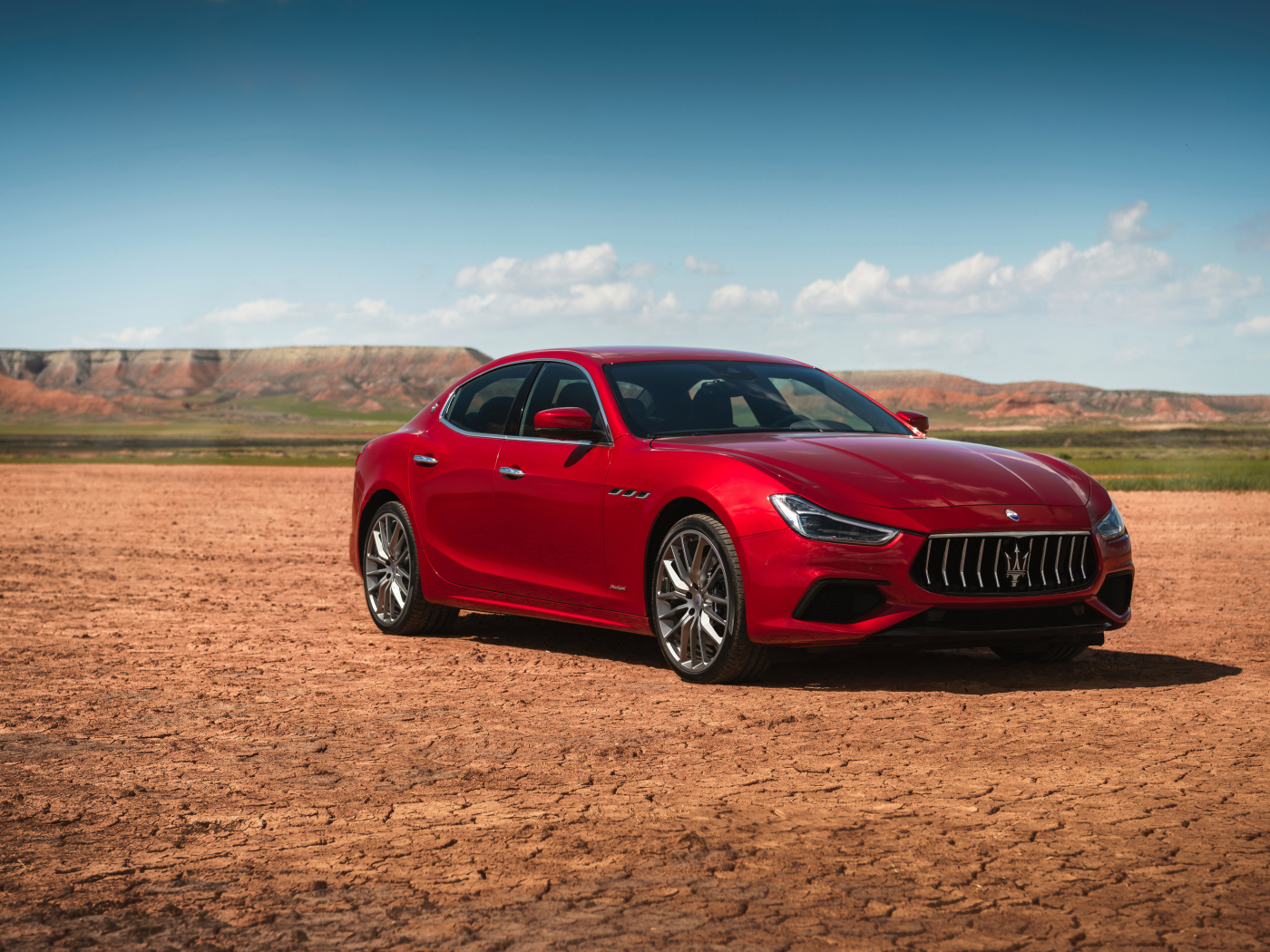 Красный автомобиль Maserati Ghibli на фоне голубого неба