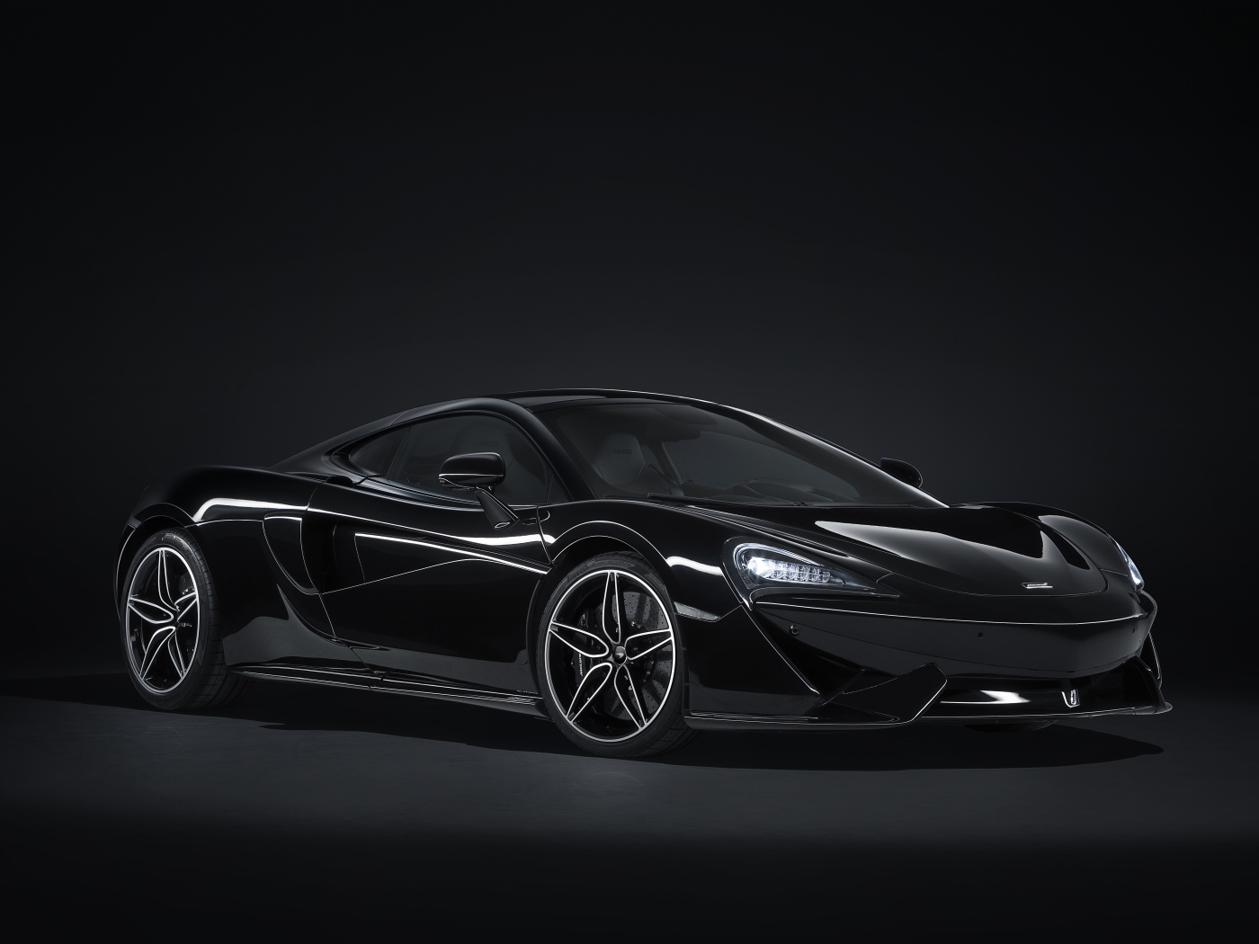 Черный автомобиль McLaren 570GT на сером фоне
