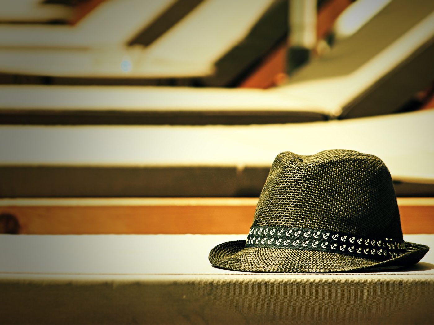Летняя шляпа лежит на лавке в лучах солнца