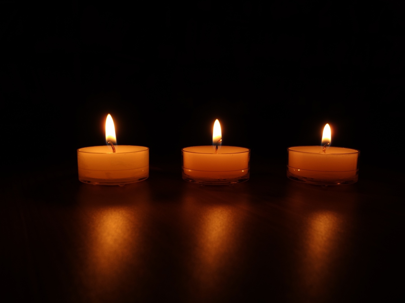 Три зажженные свечи на черном фоне