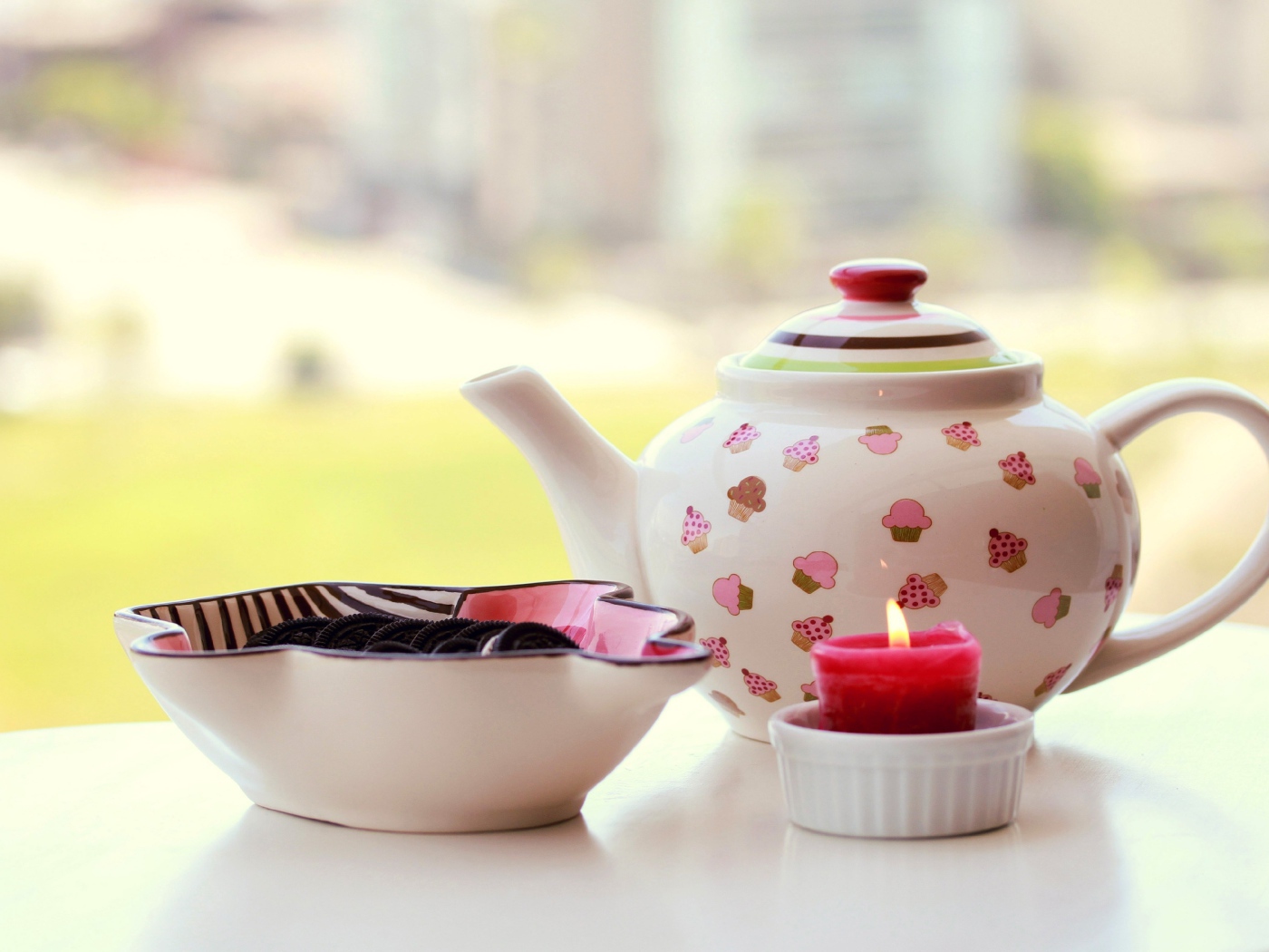 Чайник с печеньем орео и зажженной свечей на столе