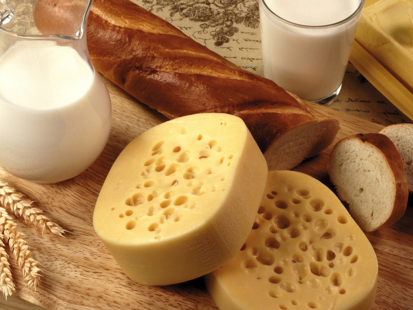 Сыр на столе с маслом, молоком и батоном 