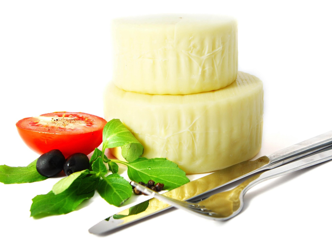 Сыр с помидором, столовыми приборами, оливками и зеленью на белом фоне