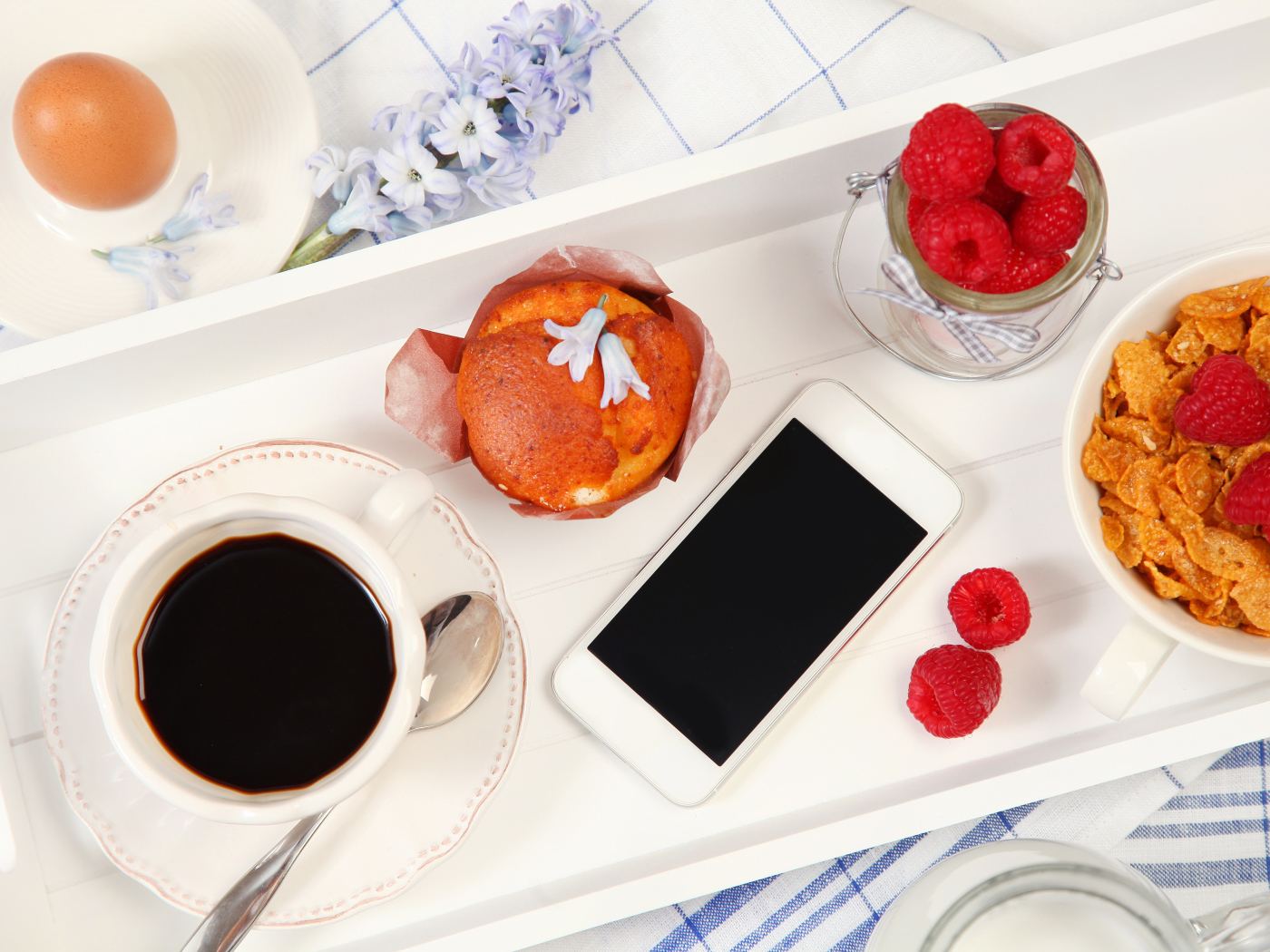 Кофе с кексом, хлопьями и малиной на столе со смартфоном 