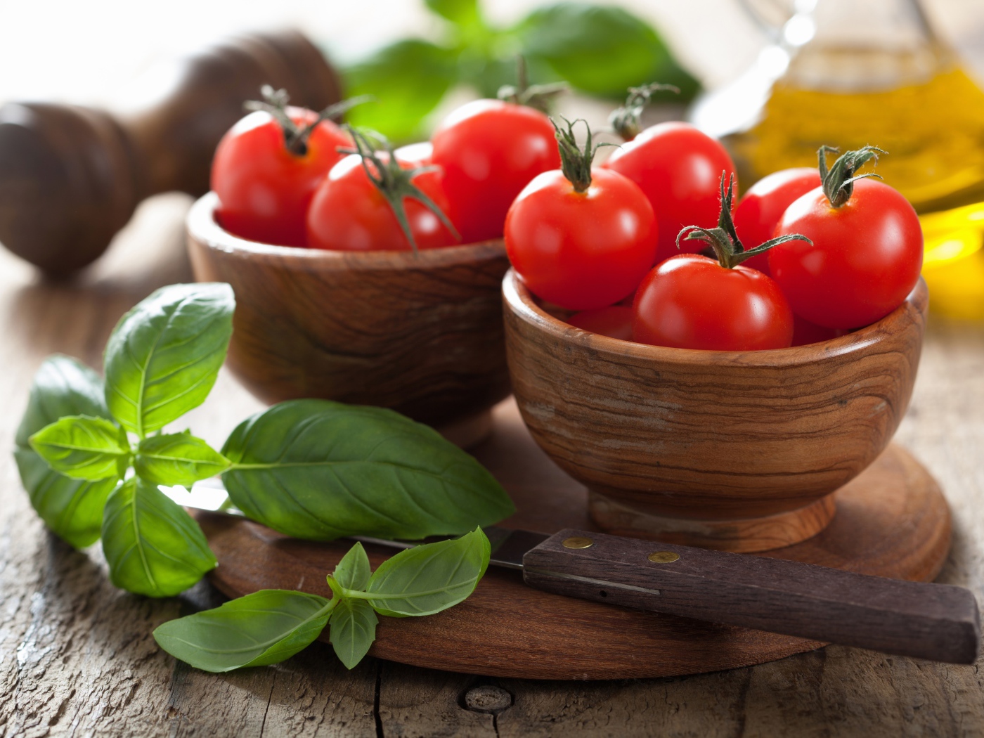 Свежие красные помидоры на столе в деревянных мисках с базиликом