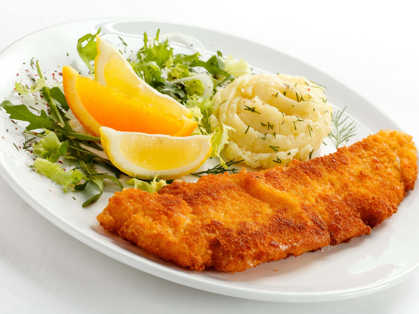 Картофельное пюре с мясом, кусочками апельсина и салатом на тарелке