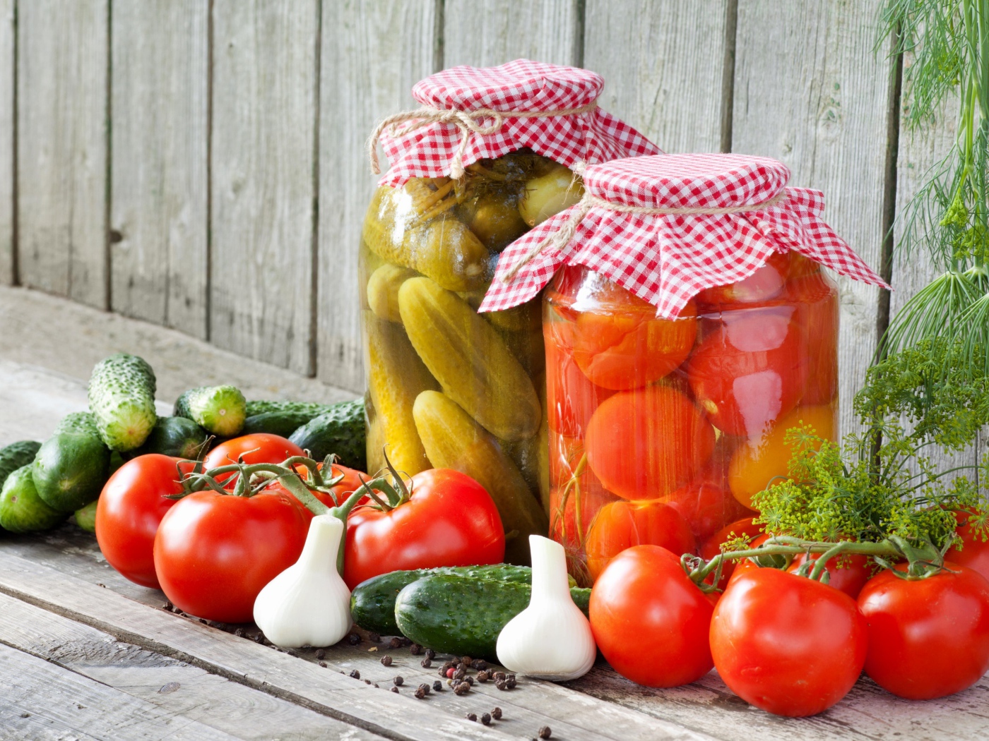 Соленья из огурцов и помидоров с овощами на столе
