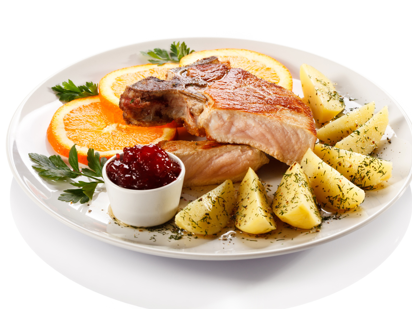 Картофель с мясом и кусочками апельсина на тарелке