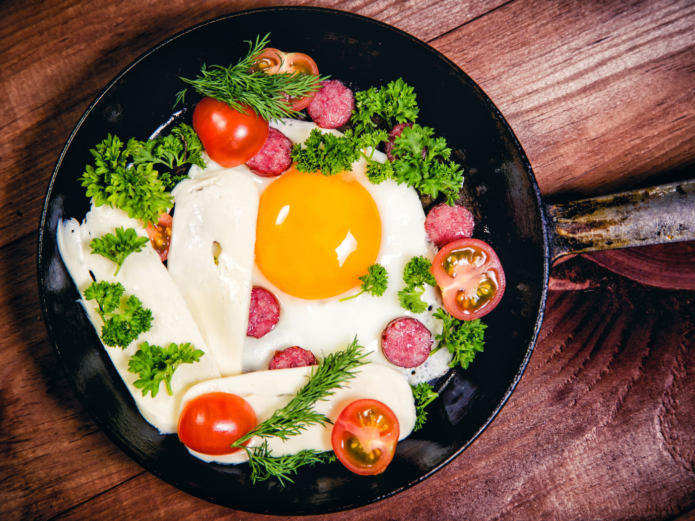 Яичница с колбасой, сыром,  помидорами и зеленью на сковороде