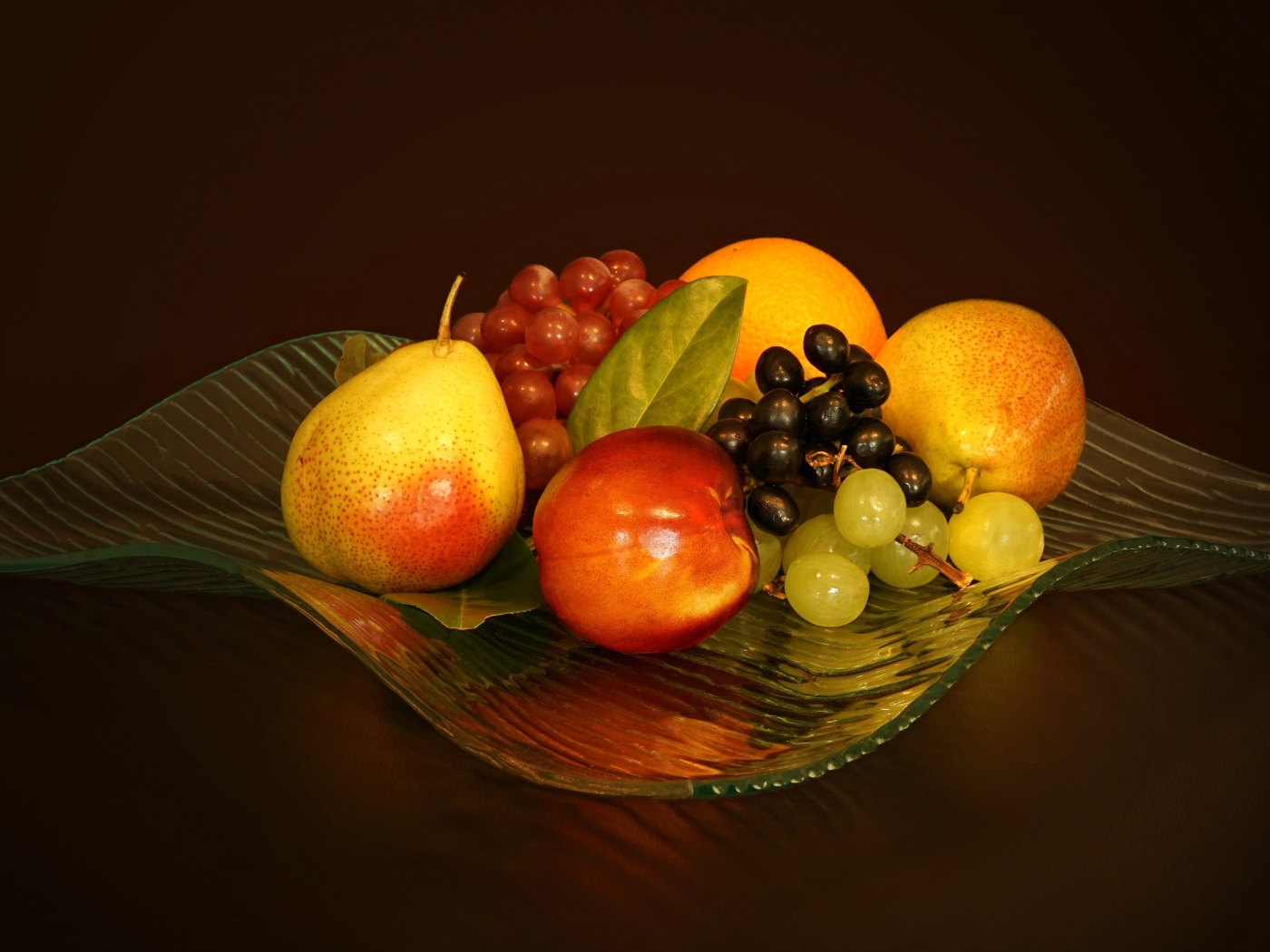 Груши, виноград, нектарин в красивой стеклянной вазе