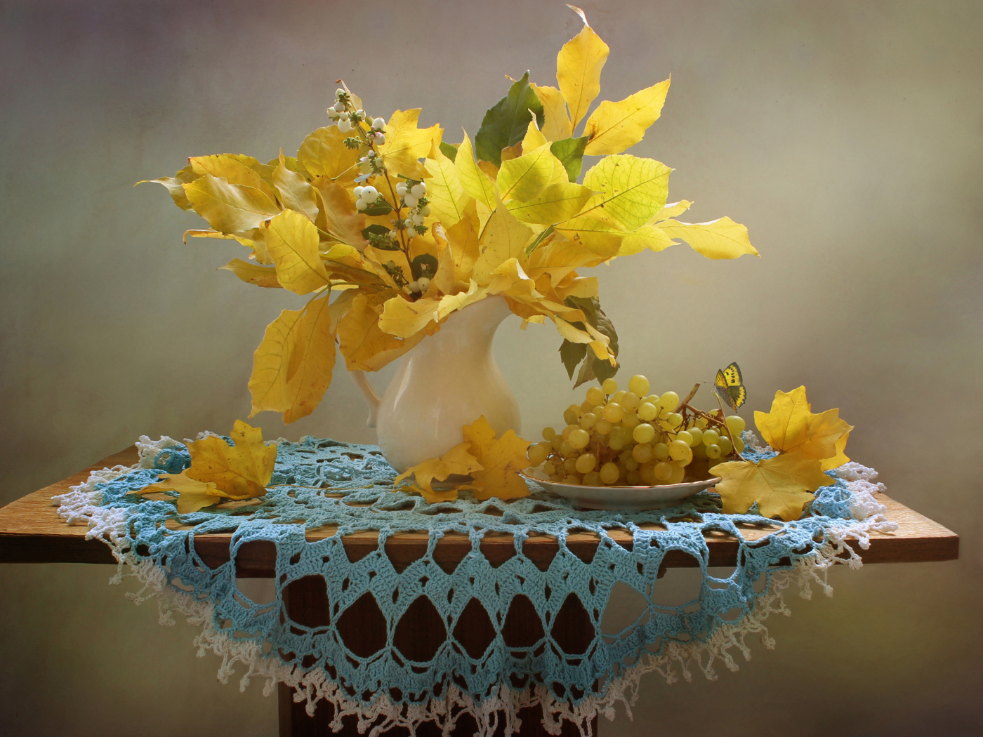 Белый виноград на столе с желтыми осенними листьями