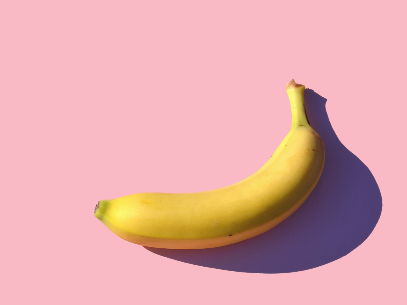 Желтый банан на розовом фоне