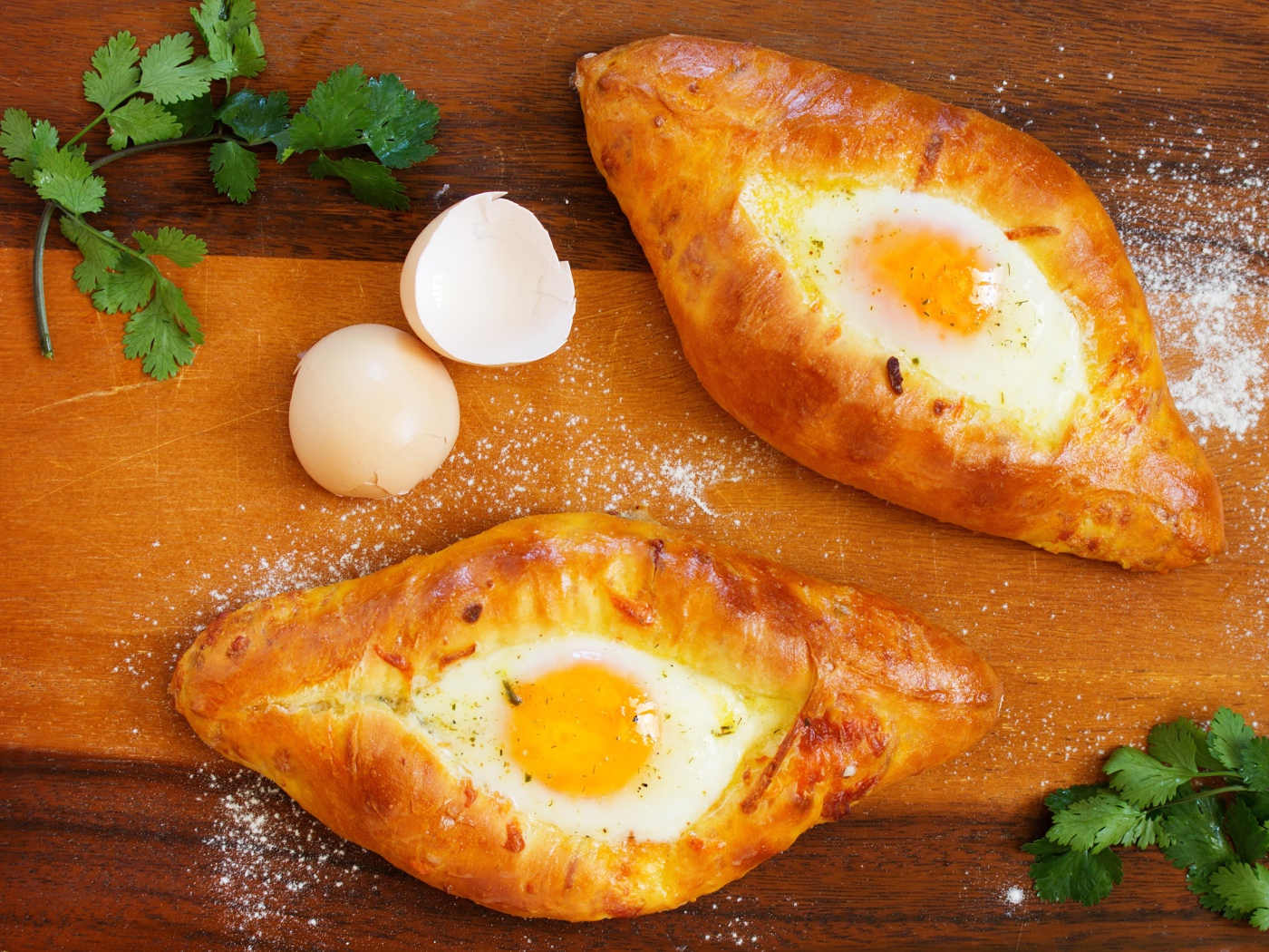 Две булки с яйцом, скорлупой и зеленью на столе