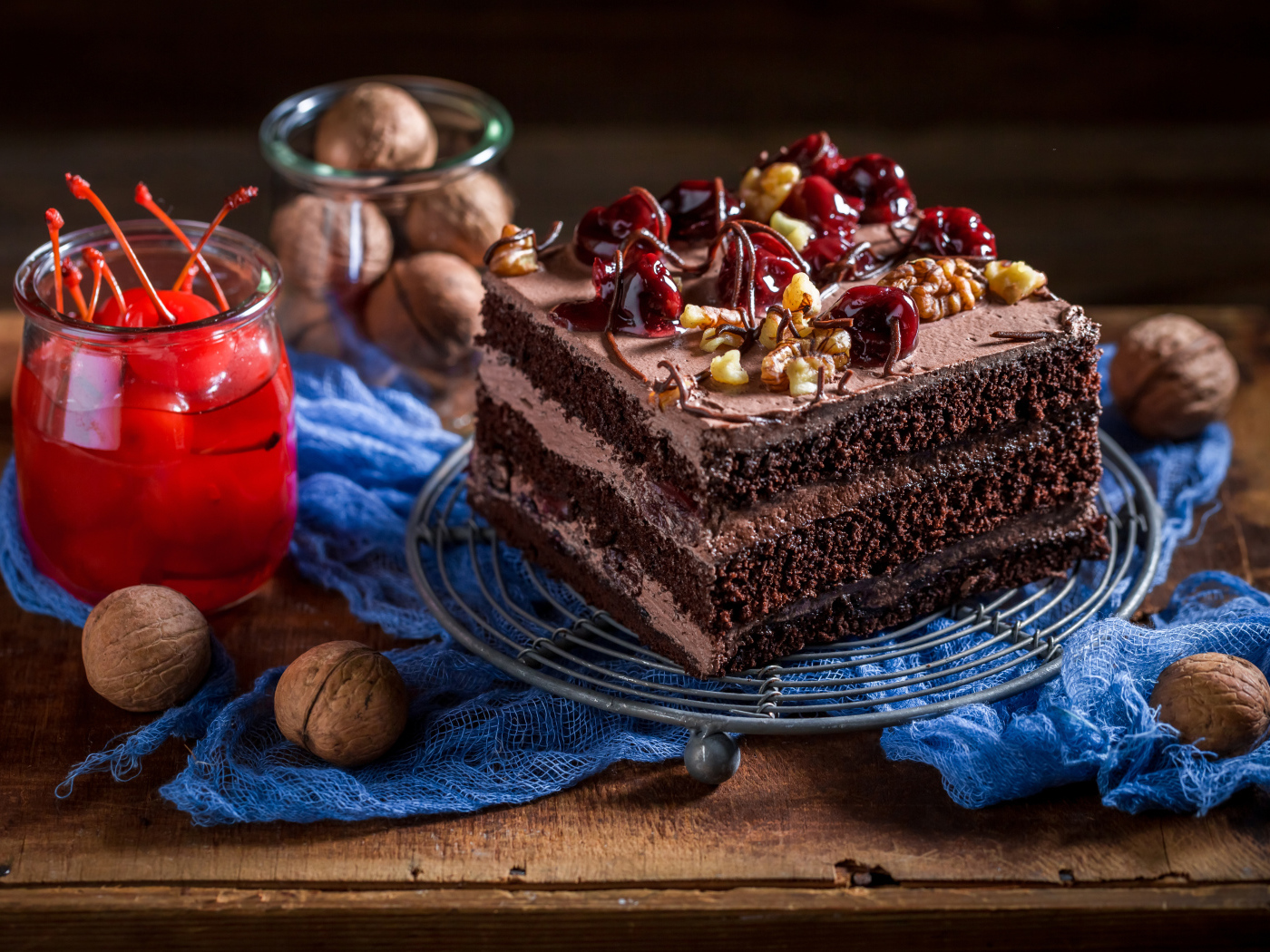 Кусок шоколадного торта на столе с вишнями и грецкими орехами