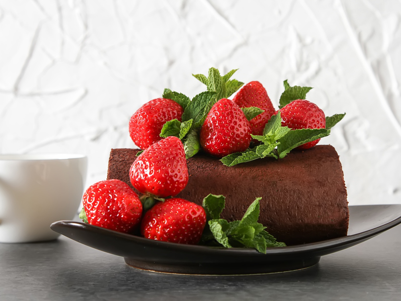 Кусок шоколадного торта со свежей клубникой на тарелке