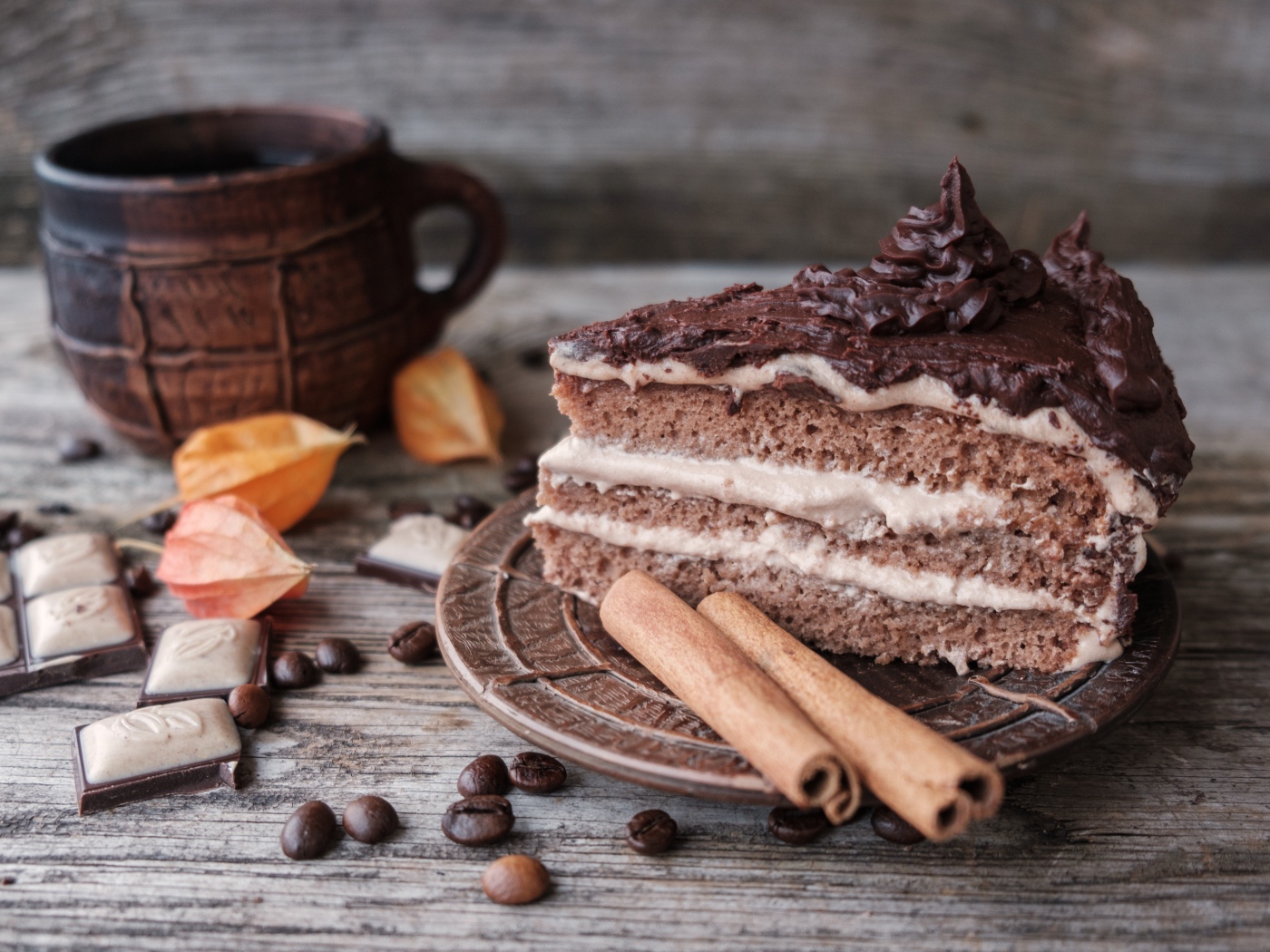 Кусок торта с корицей на столе с шоколадом и чашкой кофе