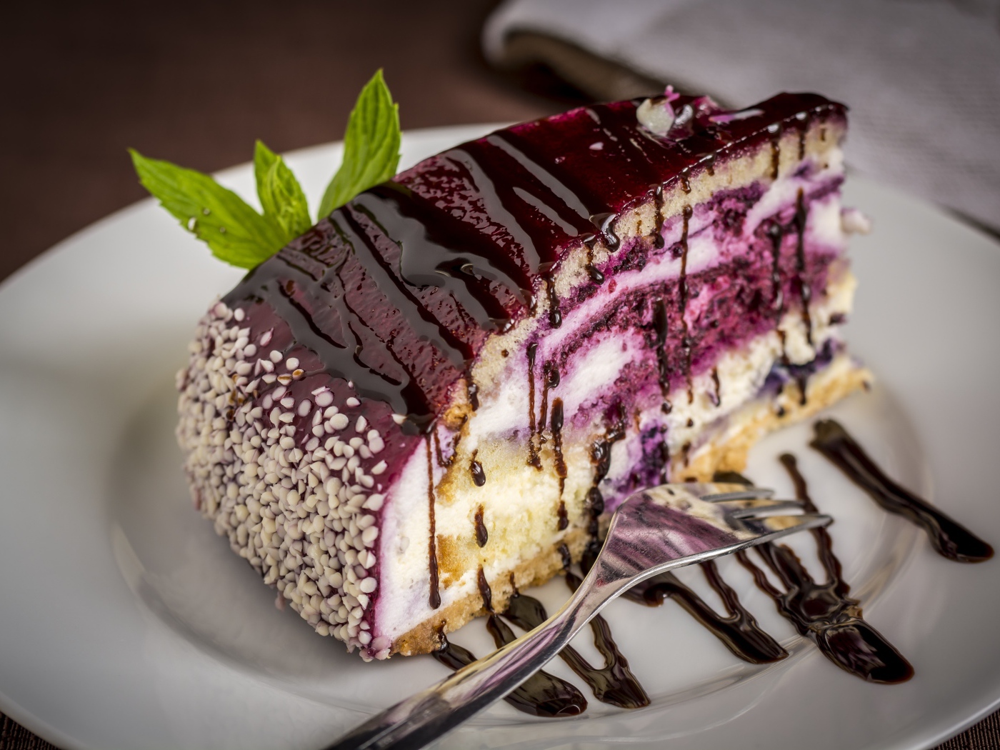 Кусок черничного пирога с джемом на белой тарелке с вилкой