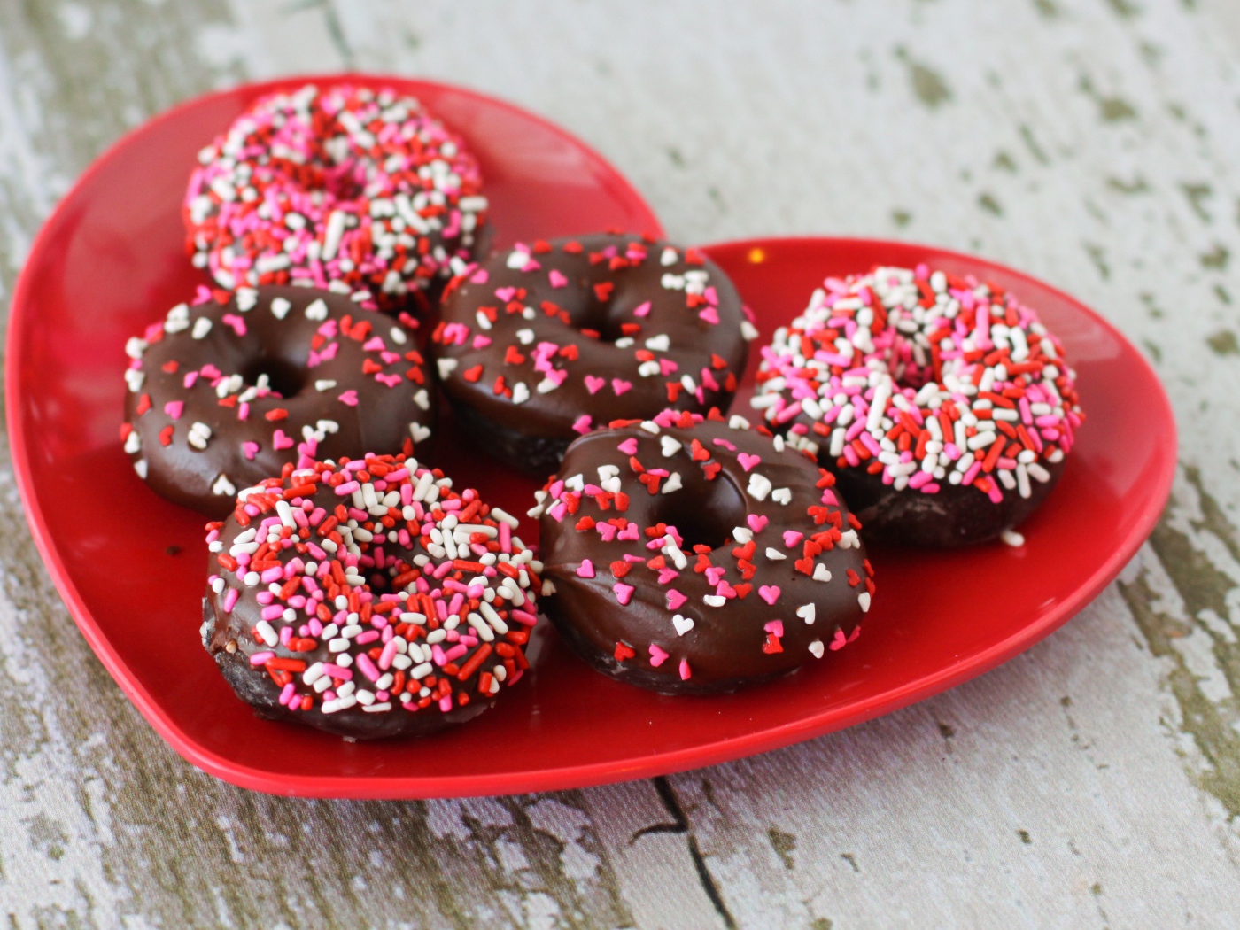 Аппетитные пончики на красной тарелке в форме сердца