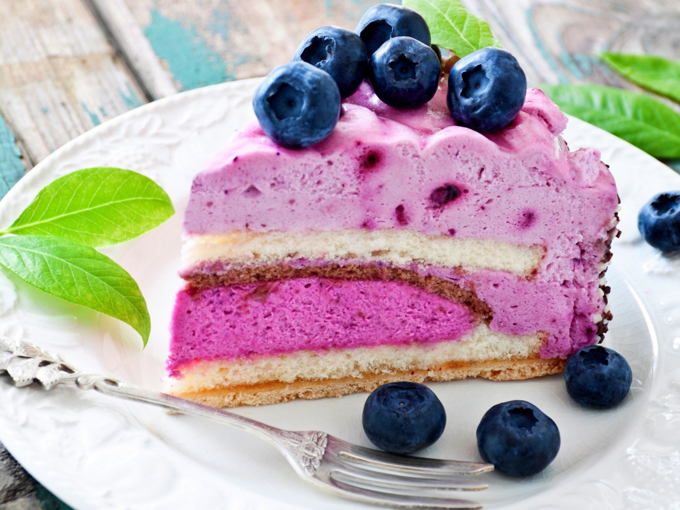 Торт с черничным муссом и свежими ягодами черники на белой тарелке 