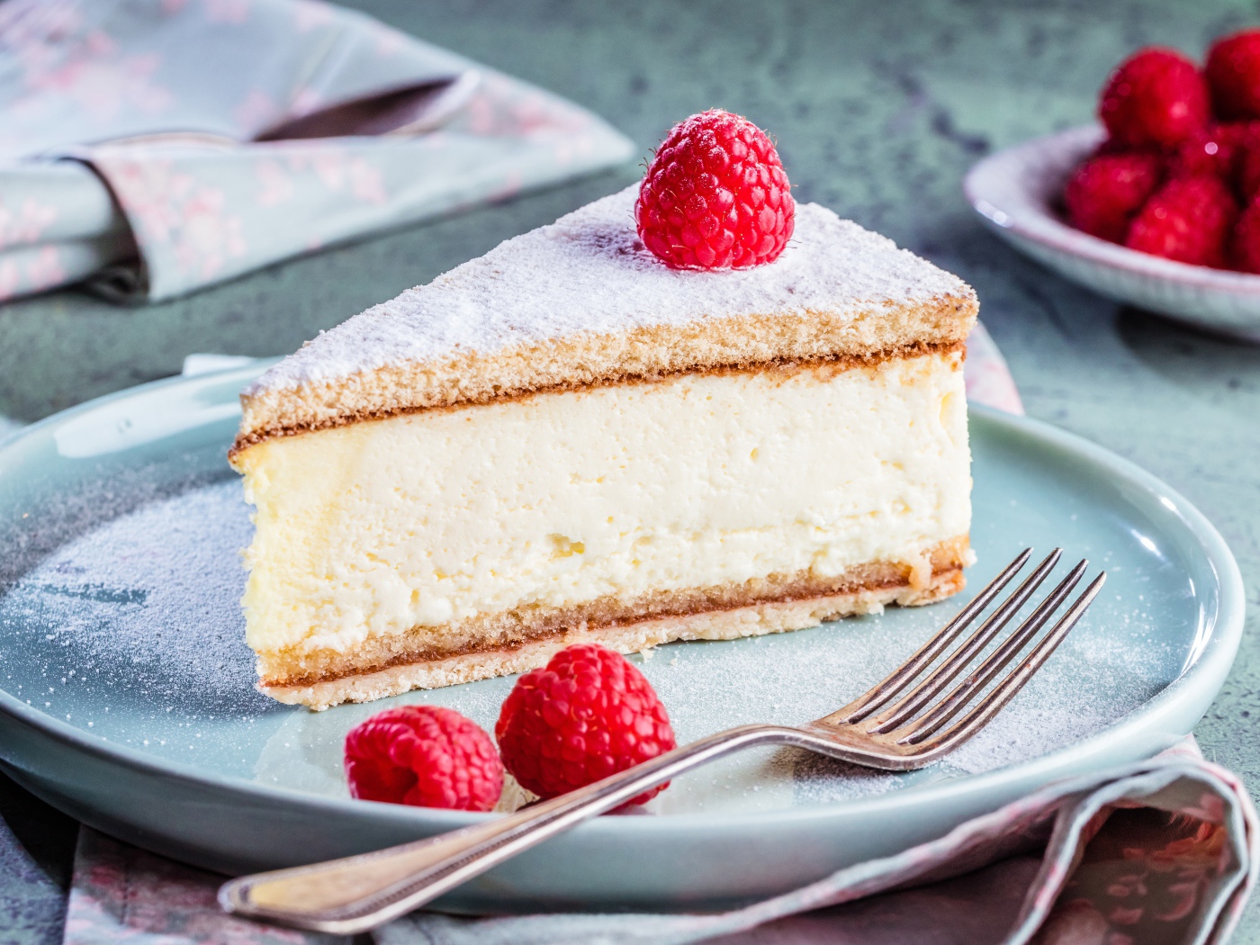 Чизкейк с сахарной пудрой и ягодами малины на тарелке