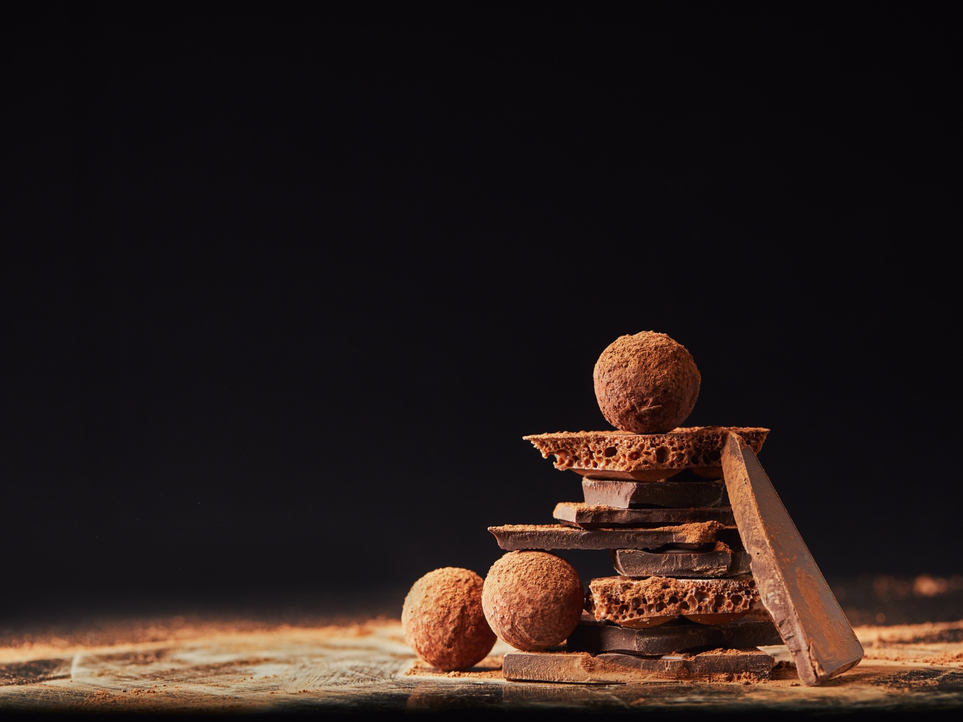 Шоколадные шарики и кусочки шоколада на черном фоне