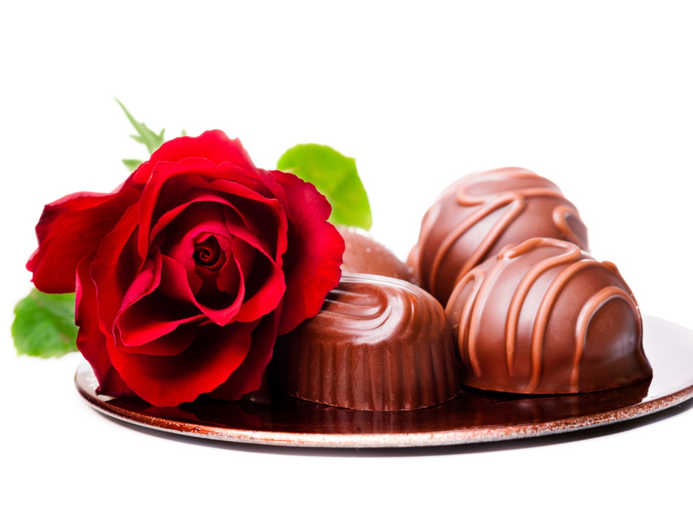 Шоколадные конфеты на тарелке с красной розой на белом фоне