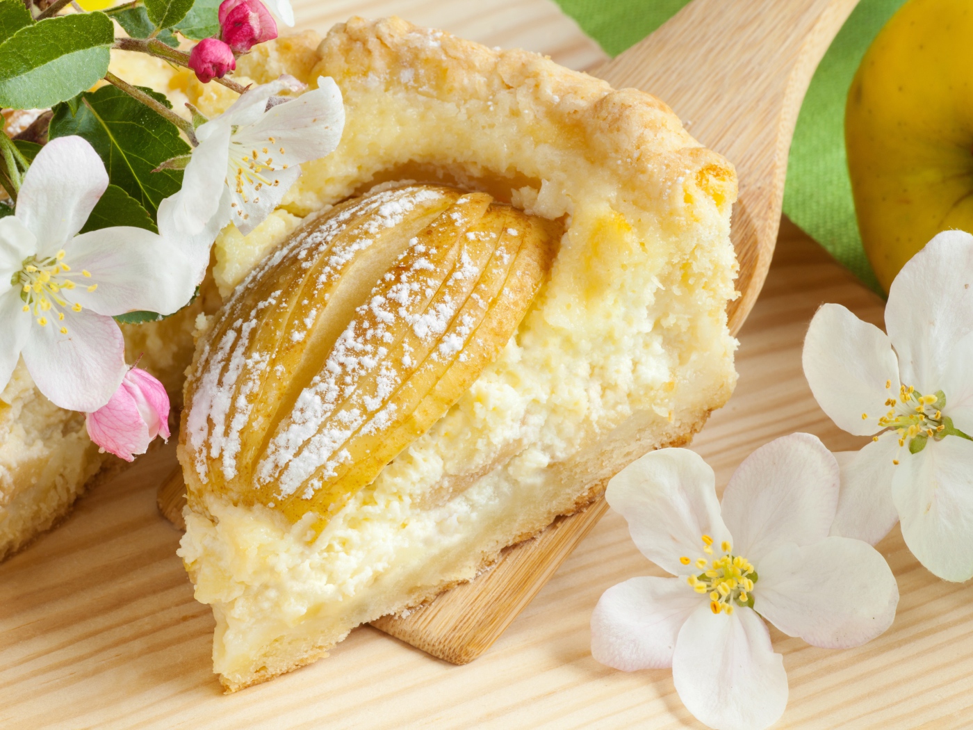 Кусок пирога с яблоками на деревянной лопатке с цветами яблони