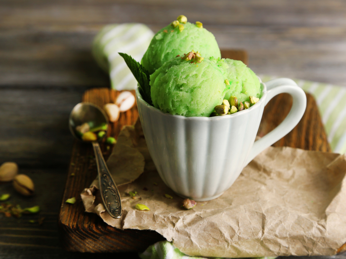 Фисташковое мороженое в белой чашке на столе