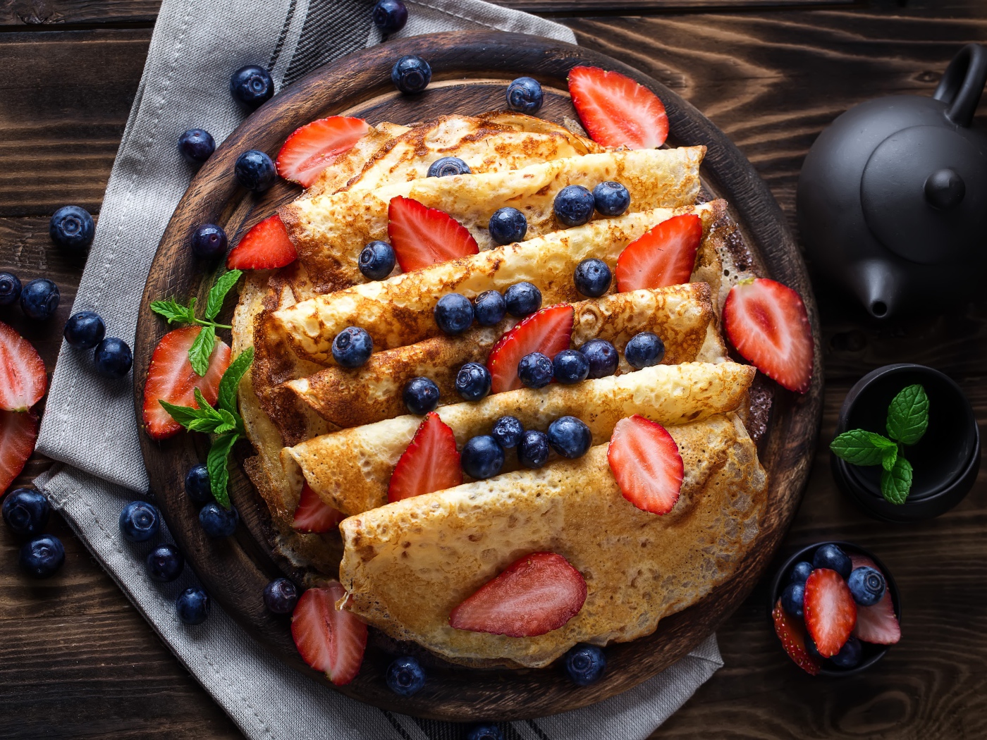 Сладкие блины с ягодами черники и клубники на столе