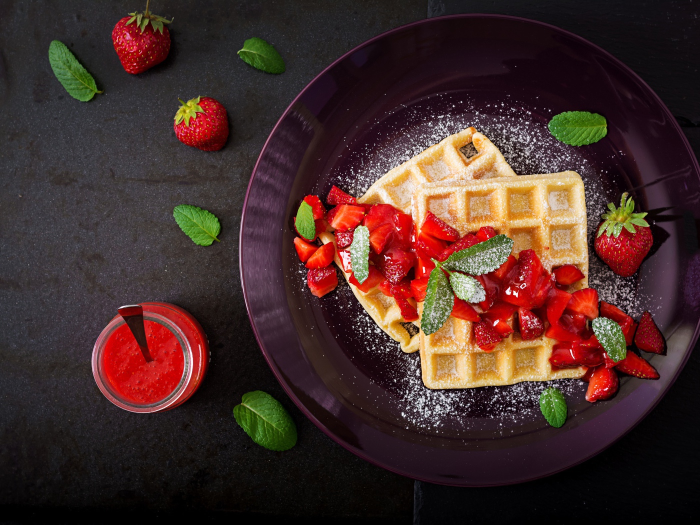 Сладкие вафли с клубникой и сахарной пудрой на тарелке 