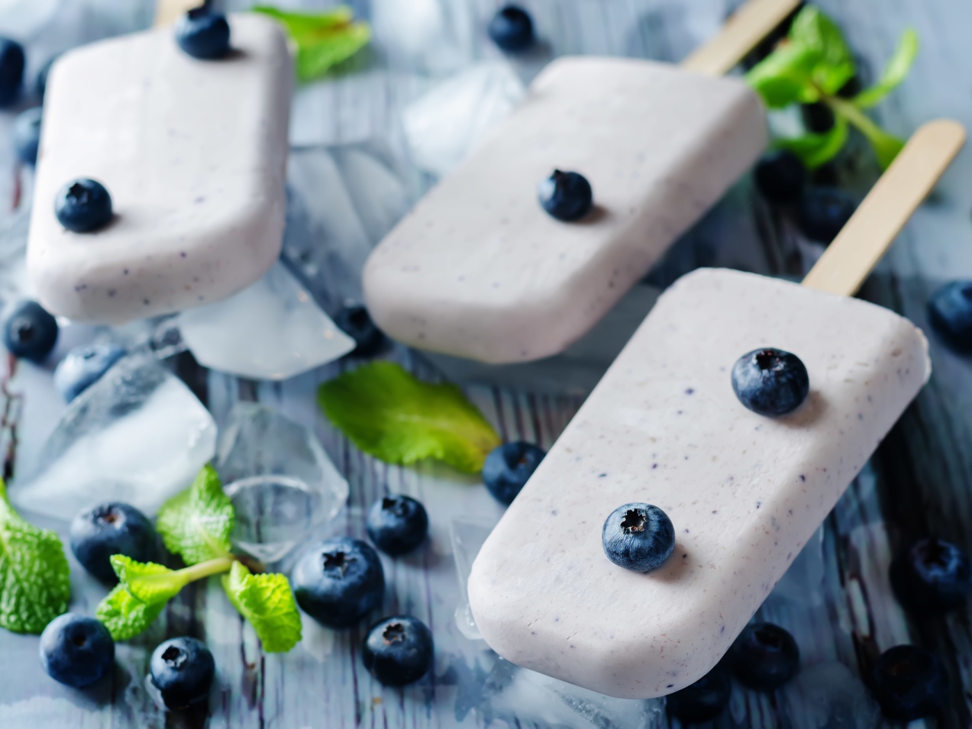 Вкусное мороженое с ягодами черники на столе с кусочками льда