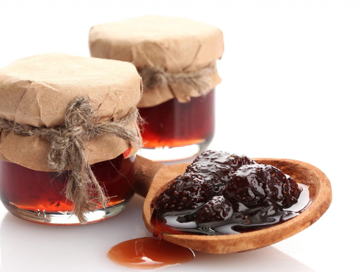 Две банки клубничного варенья на столе с ложкой 