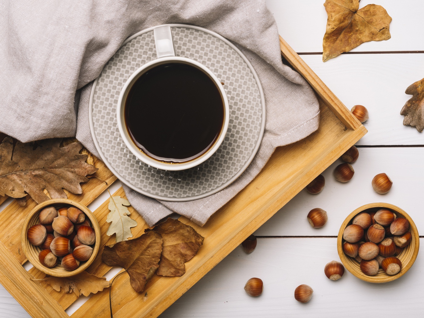 Чашка кофе на столе с лесными орехами и желтыми листьями