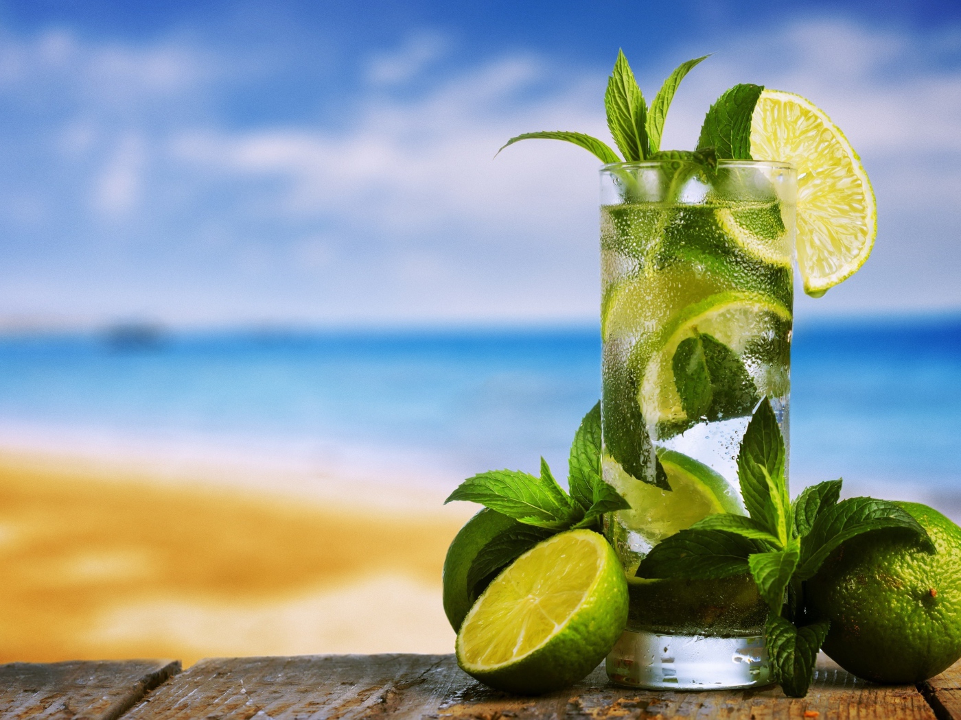 Стакан холодного мохито на столе с мятой и лаймом
