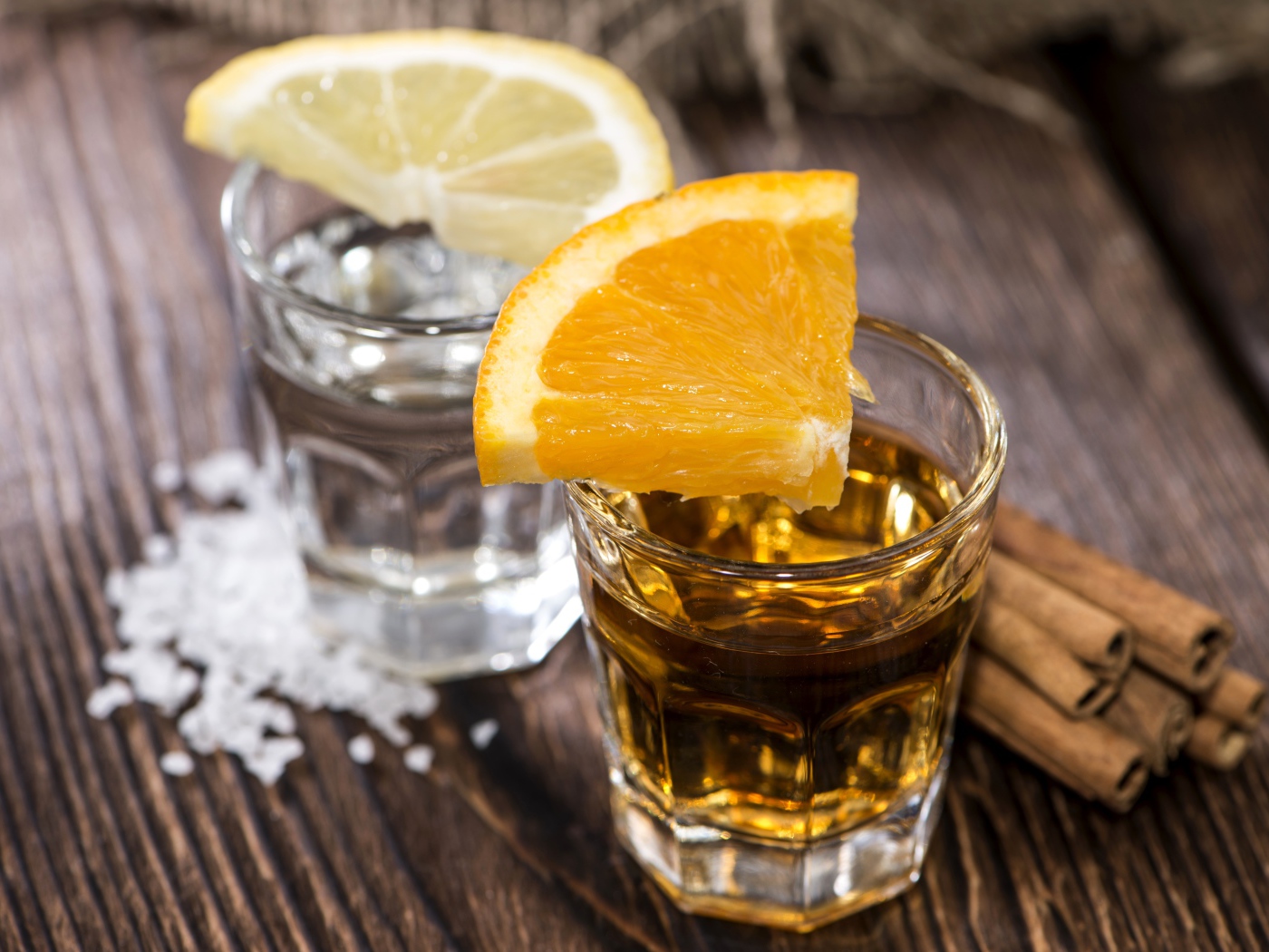 Рюмка водки и рюмка виски на столе с кусочками лимона