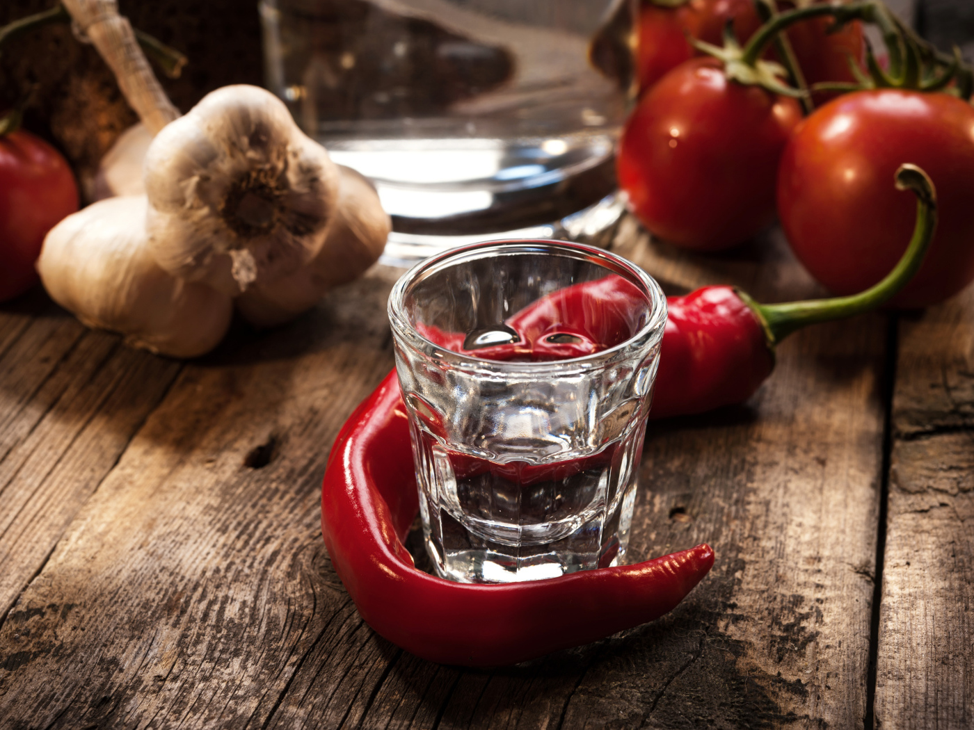 Рюмка водки на столе с красным перцем и чесноком
