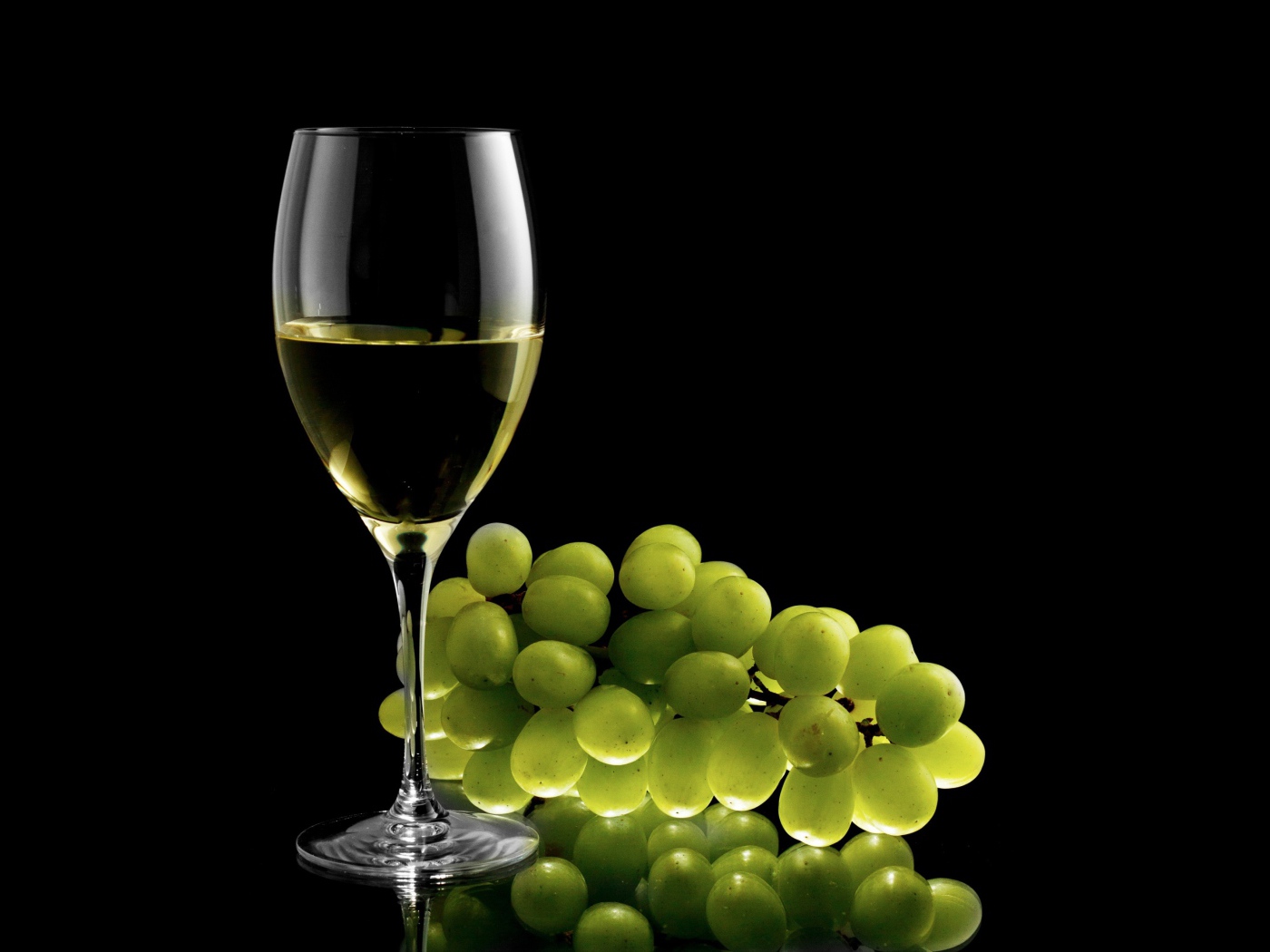 Бокал белого вина с белым виноградом на черном фоне