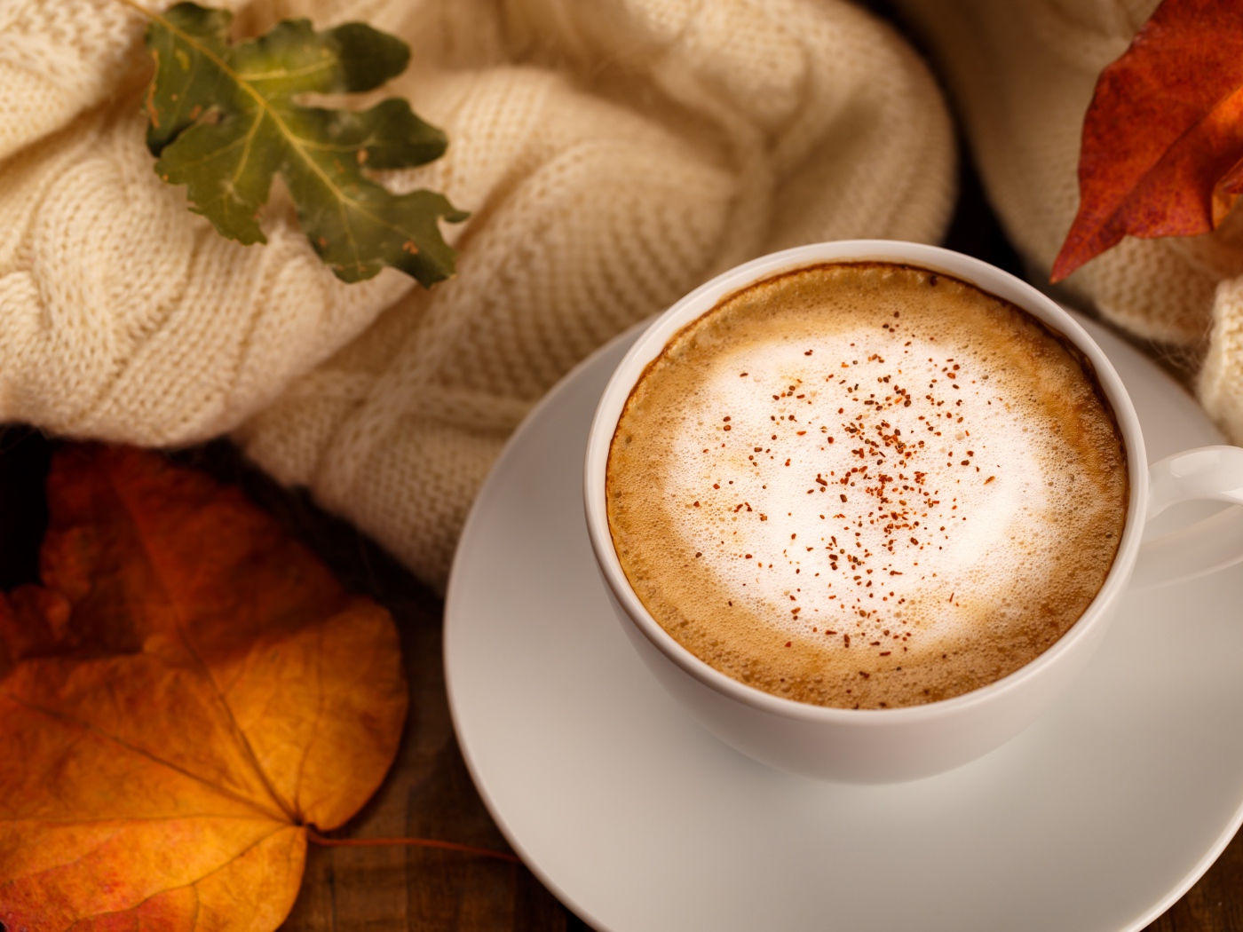 Белая чашка с вкусным кофе на столе с желтыми листьями
