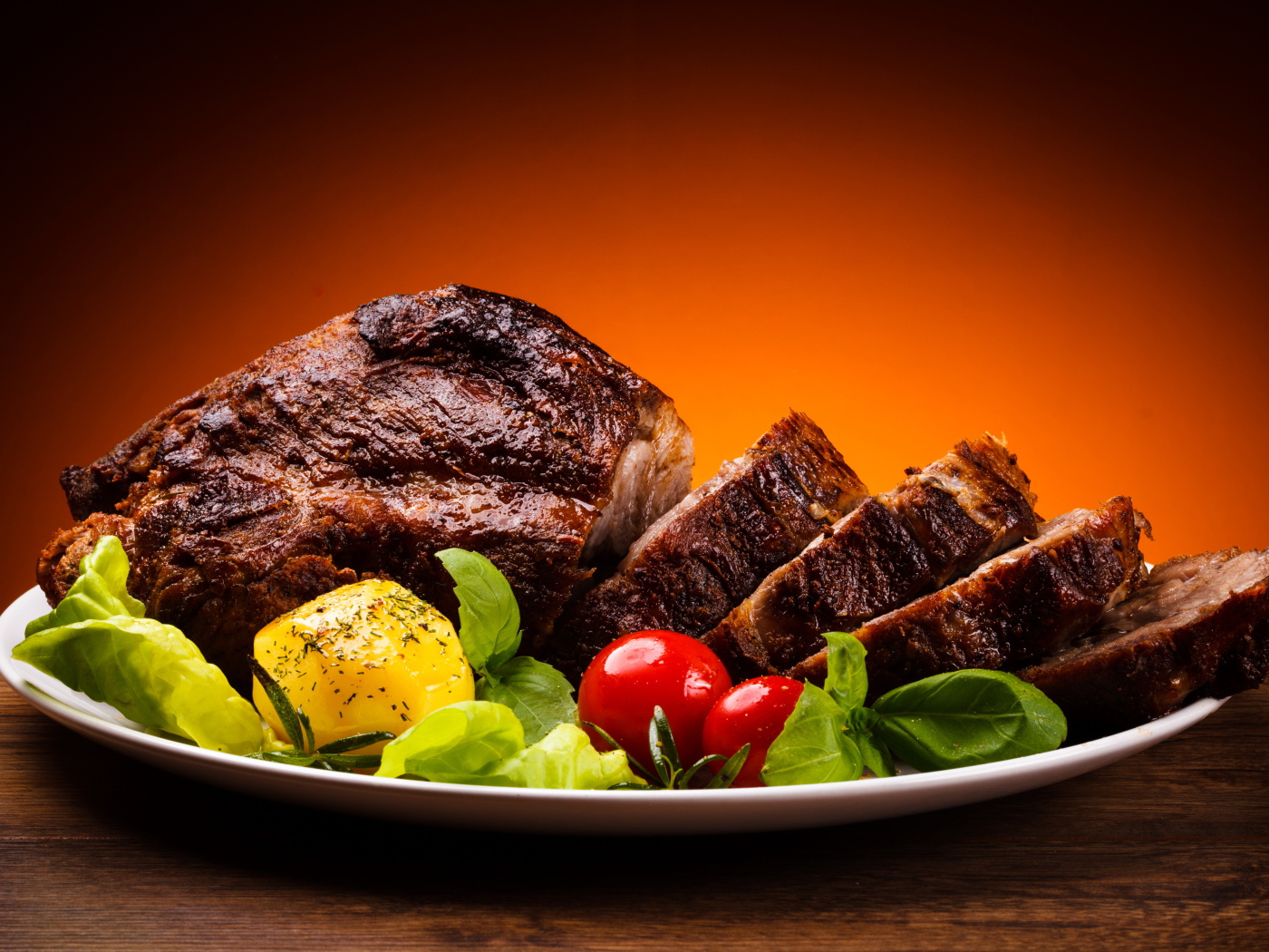 Кусок жареного мяса на тарелке с картофелем и помидорами 