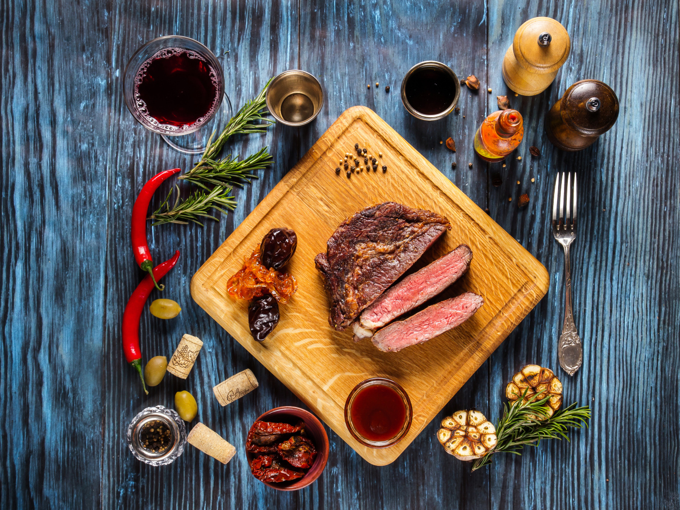 Кусок мяса на столе со специями и стаканом вина