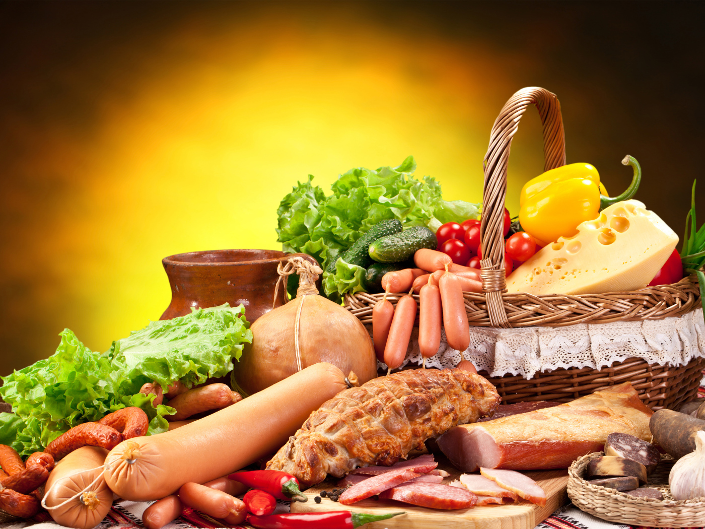 Аппетитные мясные продукты на столе с корзиной овощей