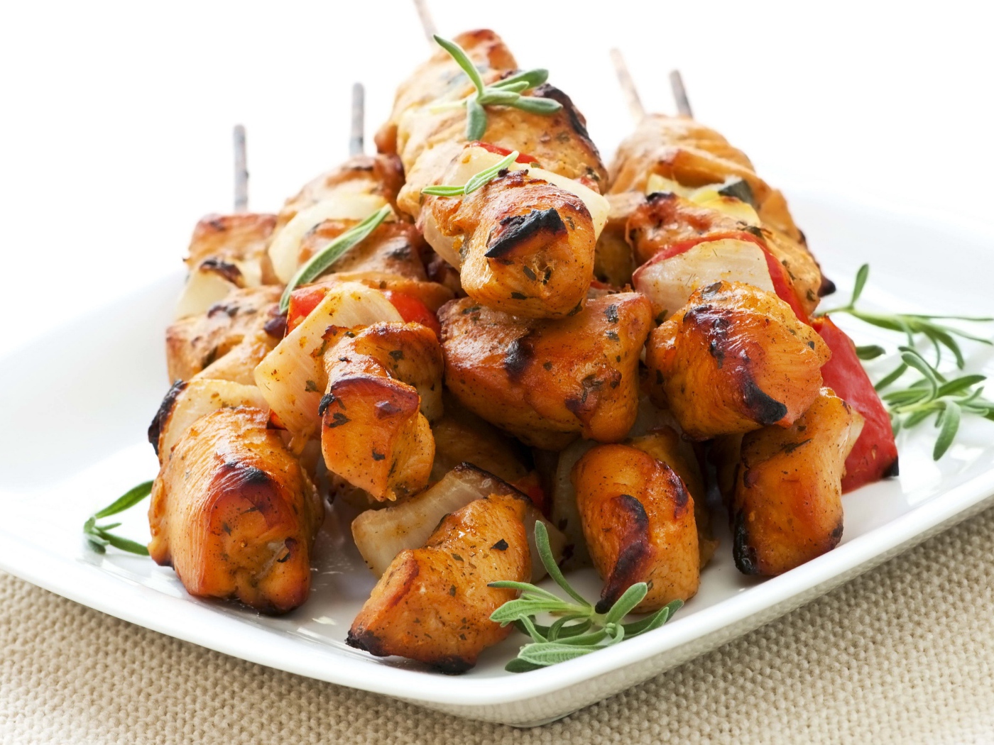 Шашлыки на белой тарелке с зеленью розмарина