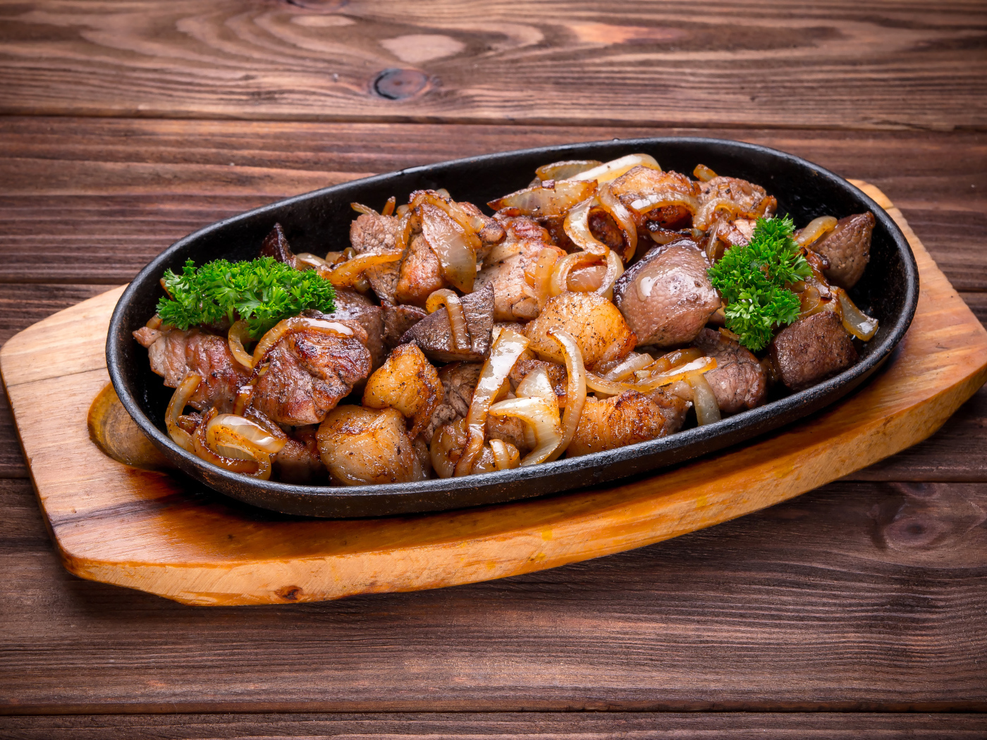 Кусочки шашлыка с луком и петрушкой в сковороде